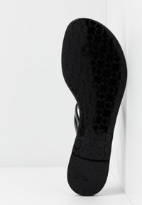 Suola nera di calzature con un motivo testurizzato di cerchi intrecciati. Presenta una finitura liscia e una forma arrotondata, etichettata "made in Italy."