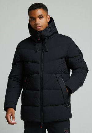 Chaqueta acolchada negra con cuello alto, cierre frontal, bolsillos laterales y patrones cosidos. Presenta ajustes de tipo toggle y acentos de logo.