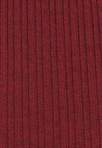 Tissu tricoté bordeaux avec des motifs verticaux en côtes et en torsades, montrant une matière en laine douce et texturée.
