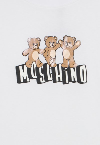 Λευκό μπλουζάκι με τρία καρτούν αρκουδάκια και έντονο κείμενο που γράφει «Moschino». Τα αρκουδάκια είναι καφέ με πιο ανοιχτές κοιλίτσες, εμφανίζοντας χαρούμενες πόζες.