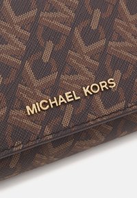 Portafoglio in tessuto marrone a motivi con logo dorato "MICHAEL KORS". Il design presenta una superficie testurizzata e motivi a catena intrecciata.