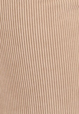 Beige ribbelstof close-up, met een zachte textuur en verticale lijnen. Het materiaal lijkt rekbaar met subtiele variatie in toon.