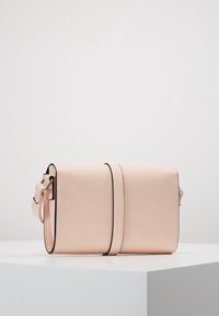 Pink faux læder crossbody taske med rektangulær form, der har en aftagelig rem og et minimalistisk design med sort kontrastsyning.