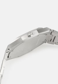 Stainless steel watch with a rectangular case. Features a brushed and polished texture, a prominent crown, and a link bracelet.