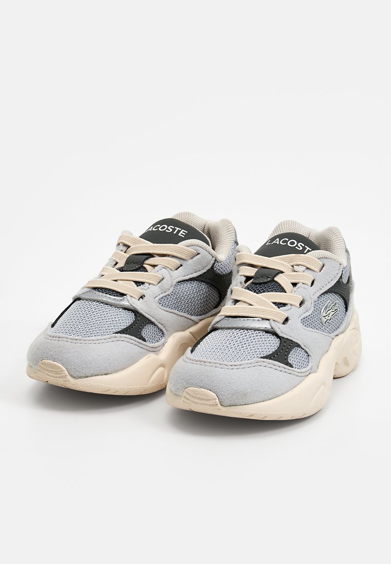 Szare buty sportowe z materiałów siateczkowych i zamszowych, z czarnym akcentem, beżową gumową podeszwą i logo na języku. Zawiązywany wzór.