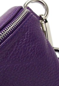 Paarse leren handtas met een gestructureerde afwerking, zilveren rits en metalen hardware accentueringen. Heeft een ritssluiting en een afgeronde vorm.