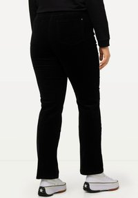 Zwarte flanellen broek met een licht hoge taille, achterzakken en een zachte textuur, gecombineerd met witte platform sneakers.