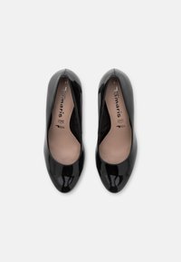 Paire de ballerines en cuir verni noir pour femme, bouts arrondis, semelles intérieures beige et nom de la marque imprimé à l'intérieur.
