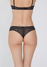 Zwart kanten lingeriesetje met ingewikkelde bloemenpatronen, verstelbare bandjes en een delicate afwerking, met een hoge snit.