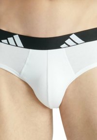 Witte herenonderbroeken van katoen met een zwarte elastische tailleband, die drie witte strepen en een logo-ontwerp bevat.