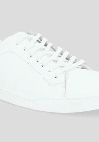 Białe skórzane sneakersy o gładkiej teksturze, okrągłym czubku i tradycyjnym wiązaniu z minimalnymi detalami.