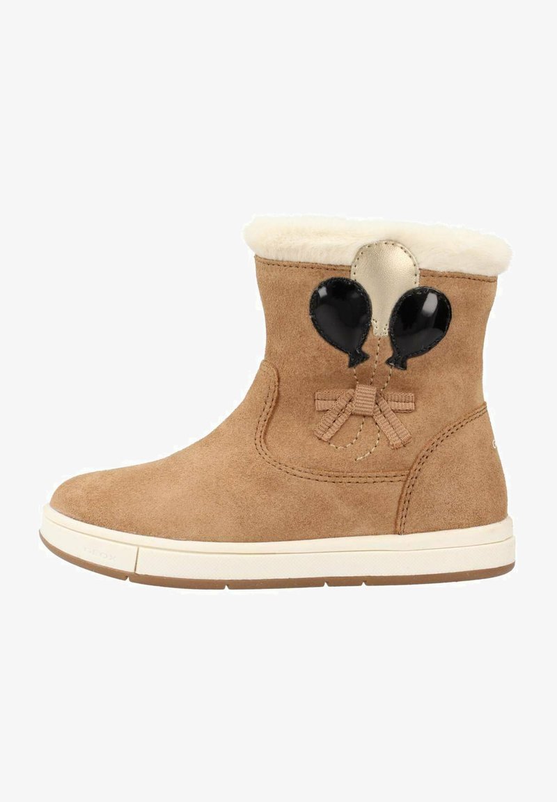 Botas de tobillo de ante en color trigo con un cuello de piel sintética, que cuentan con acentos de globos negros y un detalle de lazo. Suela de goma para mayor tracción.