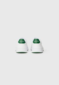 Witte sport schoenen met groene accenten op de hiel en het logo. Beschikbaar met een gladde leren bovenkant en een gestructureerde rubberen zool.