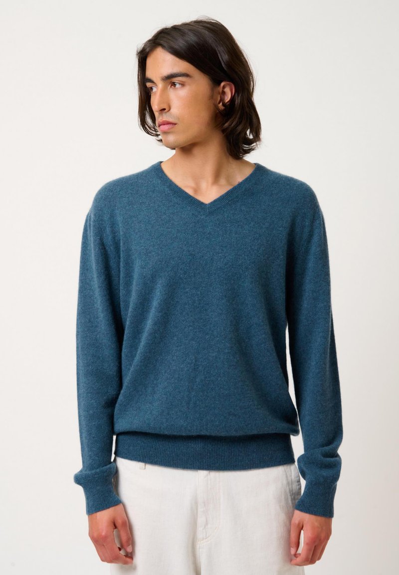 V-Ausschnitt Pullover in tiefblau, aus weichem Stoff gefertigt, mit langen Ärmeln sowie gerippten Bündchen und Saum.