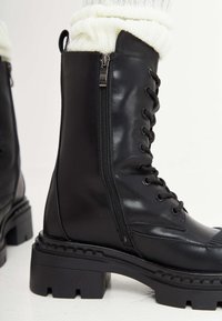 Zwarte leren veterschoenen met een zijrits, een stevige zool en textuuraccenten. Voorzien van een afgeronde neus en versterkte stikseldetails.