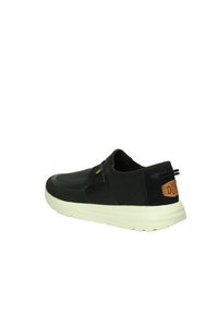 Scarpa nera slip-on realizzata in rete traspirante con una finitura texturizzata, dotata di una suola bianca e di un accento in pelle marrone sul tallone.