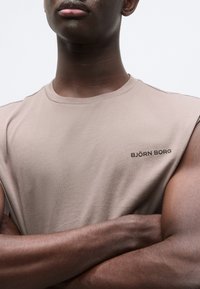 Αμάνικο μπεζ T-shirt από βαμβάκι, με στρογγυλή λαιμόκοψη και μαύρο λογότυπο "BJÖRN BORG" στο κάτω αριστερό μέρος. Λεπτή υφή.