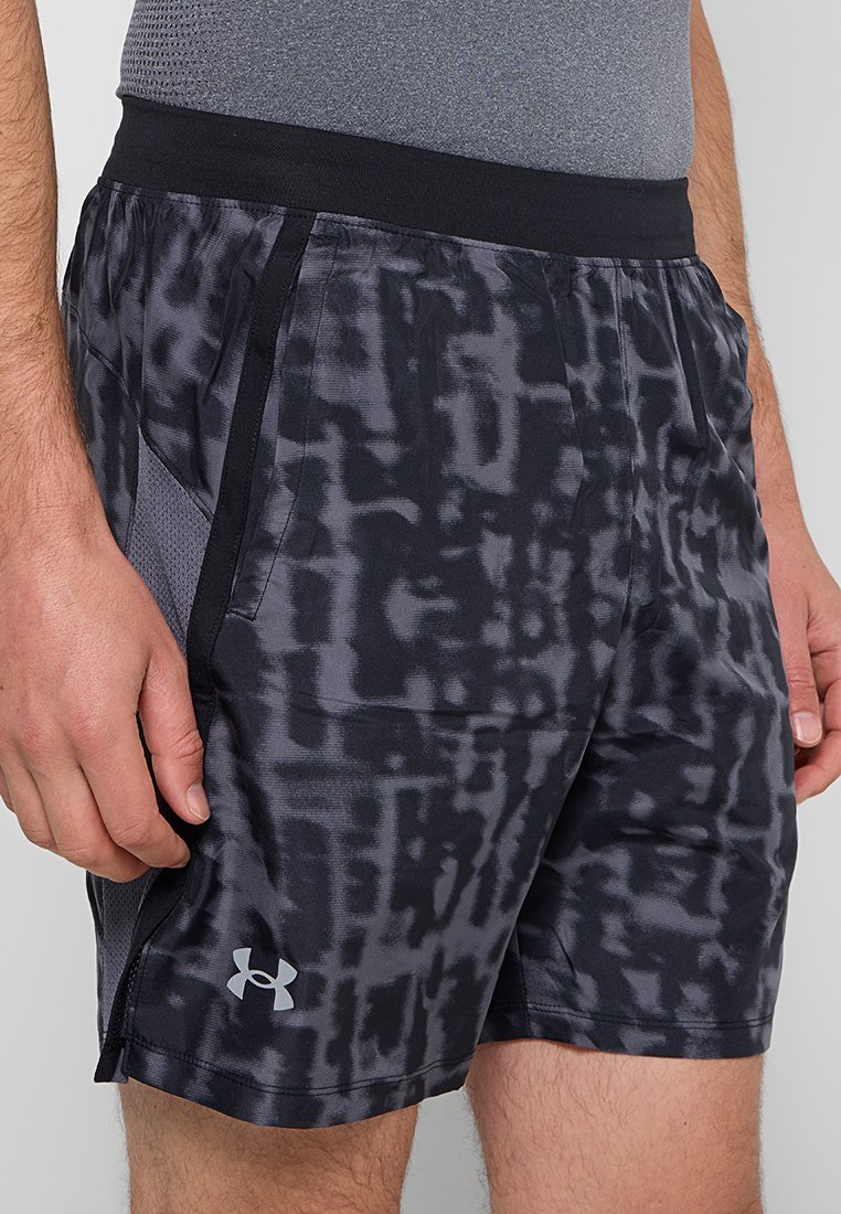 Homme portant un short de sport noir et gris avec des panneaux latéraux en maille et le logo Under Armour près de l'ourlet.