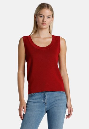 Rotes ärmelloses Oberteil mit einem Rundhalsausschnitt, aus strukturierter Stoff gefertigt, kombiniert mit hellblauen Jeans für einen lässigen Look.