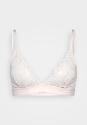 Bralette en dentelle rose clair avec des bonnets triangulaires, des bords festonnés et une bande douce arborant un logo répété. Bretelles ajustables.