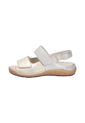 Sandale blanche à bout ouvert avec des brides velcro ajustables, une semelle en liège et une boucle argentée sur la bride de cheville.