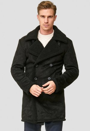 Abrigo negro de doble botonadura hecho de material similar al ante, con un cuello de borrego y puños, con bolsillos frontales y un acabado texturizado.