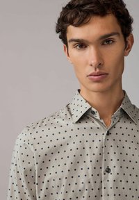Helles graues Hemd mit navyblauen Punkten, ausgestattet mit einem Button-Down-Kragen und kurzen Ärmeln, aus glattem Stoff mit leichtem Glanz.