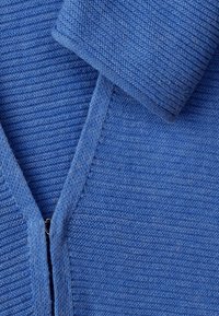 Blauwe gebreide kleding met V-hals en ribbeltextuur, met een opgevouwen mouw en gedetailleerde stiksels.