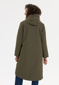 Olijfgroene, waterafstotende jas met een capuchon, middellange ontwerp en lange mouwen. Gladde textuur; geen zichtbare hardware of patronen.