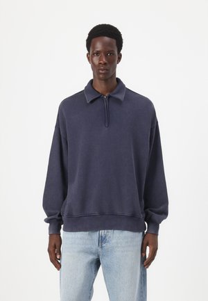 Navy blue half-zip sweatshirt made from soft fabric, featuring a collar and cuffed sleeves. Distressed texture and relaxed fit.