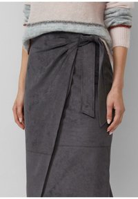 Grauer Wickelrock aus Wildleder mit gebundenem Akzent in der Taille, zeichnet sich durch eine glatte Textur und ein leicht verlängertes Design aus.