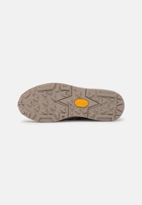 Außensohle eines Schuhs in hellbeige mit strukturiertem Gummimuster. Merkmale sind ausgeprägte dreieckige und kantige Griffe sowie ein gelbes Vibram-Logo.