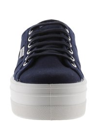 Marinblå canvas sneakers med vit gummiplattformssula, snörning framför och metallöglor. Sidologotagg synlig. Texturerad sula för grepp.