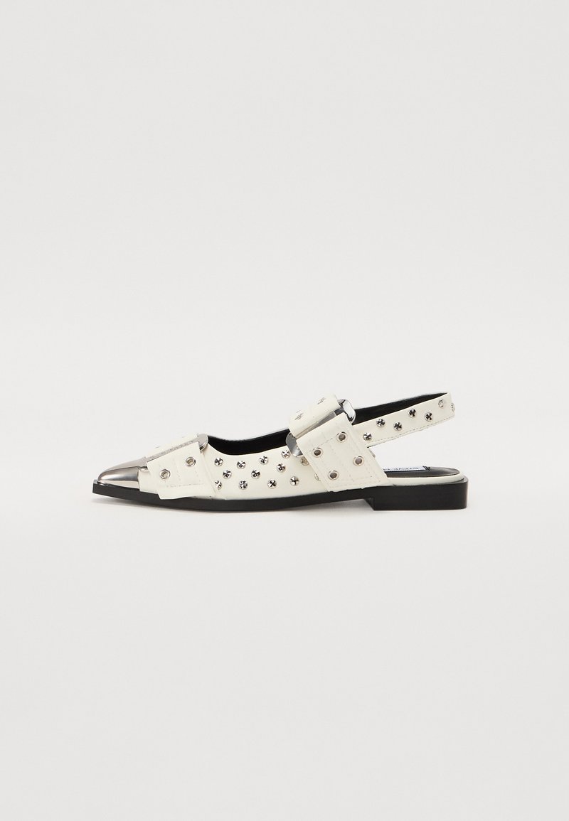 White slingback shoes with a pointed toe, metallic cap, studded accents, and dual buckle strap design. Flat black sole with textured details.