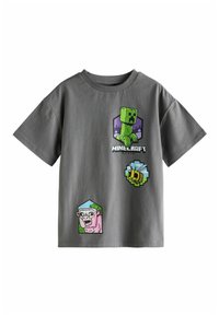 Hallha valge puuvillane T-särk, millel on värvilised pikselkunstide graafikad rohelise tegelase, roosa lambakese, mesilase ja "Minecraft Movie" teksti kujul.