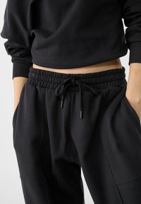 Zwarte sweatpants met een elastische tailleband, koord en zijzakken. Zachte stof met een relaxte pasvorm en op maat gemaakte naden.