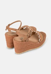 Tan suede sleef wedgesandalen met gevlochten accenten, verstelbare enkelband en een textuur touwdetail op de hiel. Plat rubberen zool voor grip.