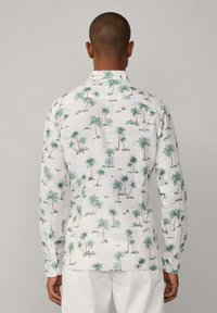 Camisa de manga larga blanca con un estampado de palmeras en verde y naranja. Tejido texturizado con cuello y puños abotonados.