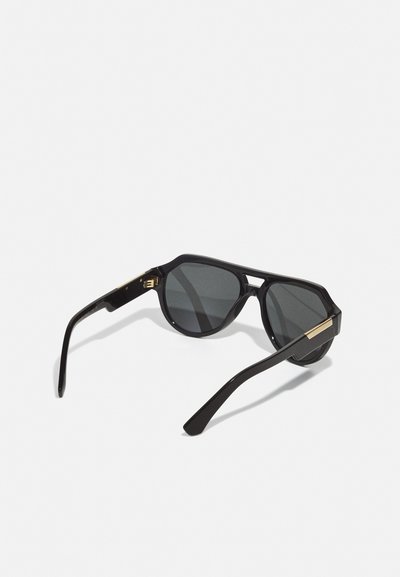 Black sunglasses with gray lenses. Angular frame design made of plastic, features gold accents on the temples. Clean, minimalist style.