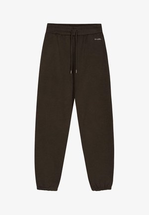 Rudos sportinės kelnės su elastinga juostele, reguliuojama raišteliu ir elastinėmis rankovėmis ties kulkšnimis. Minimalus prekių ženklas. Minkšta tekstūra.