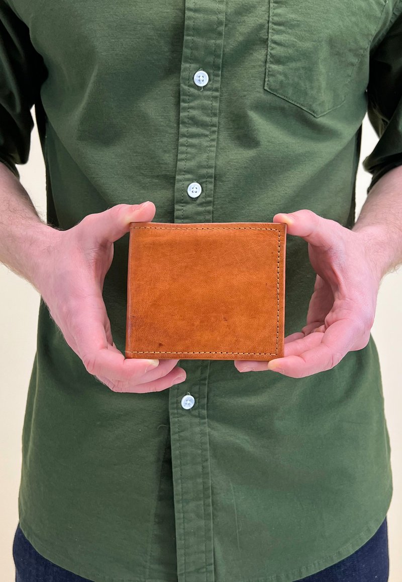 Brown leather wallet with visible stitching, presented in hands, featuring a smooth texture and flat rectangular shape.