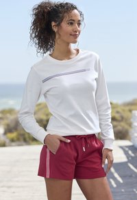 White long-sleeve top with a horizontal striped accent and maroon shorts featuring side stripes. Casual, relaxed fit with pockets.