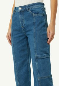 Niebieskie dżinsowe spodnie cargo z wysokim stanem, przednimi kieszeniami, kieszenią cargo z boku i luźnym krojem. Posiadają standardowe zapięcie na guzik.