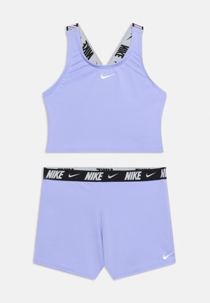 Λιλά αθλητικό σουτιέν Nike με μαύρα και λευκά λουριά με λογότυπο και ταιριαστό λιλά σορτσάκι με μαύρη ζώνη μέσης με λογότυπο Nike.