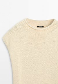 Pull sans manches en tricot couleur crème avec un col rond et une étiquette Massimo Dutti à l'intérieur du col.