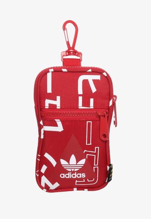 Bustina rossa Adidas con testo astratto bianco, tasca frontale con cerniera e clip rossa per attacco.