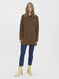 Brown oversized knit sweater, blue denim jeans, and yellow ankle boots with a square heel. Relaxed fit and long sleeves.