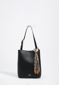 Bolso tote de cuero negro con acabado texturizado, con una correa larga y un pañuelo estampado anudado en un lado. Logotipo de la marca visible en la parte inferior.