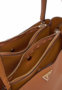 Borsa a tracolla in pelle marrone con zip e hardware dorati. Presenta due scomparti con una superficie liscia e un accentuazione a triangolo del logo.