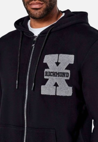 Felpa nera con zip che presenta un grande logo grigio "X RICHMOND" sul petto, con ricamo testurizzato. Il tessuto sembra morbido e confortevole.